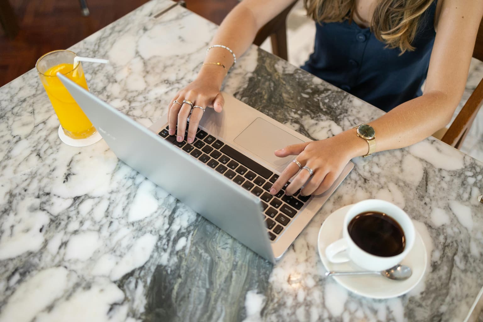 A woman using a laptop at a cafe table to start her consultation